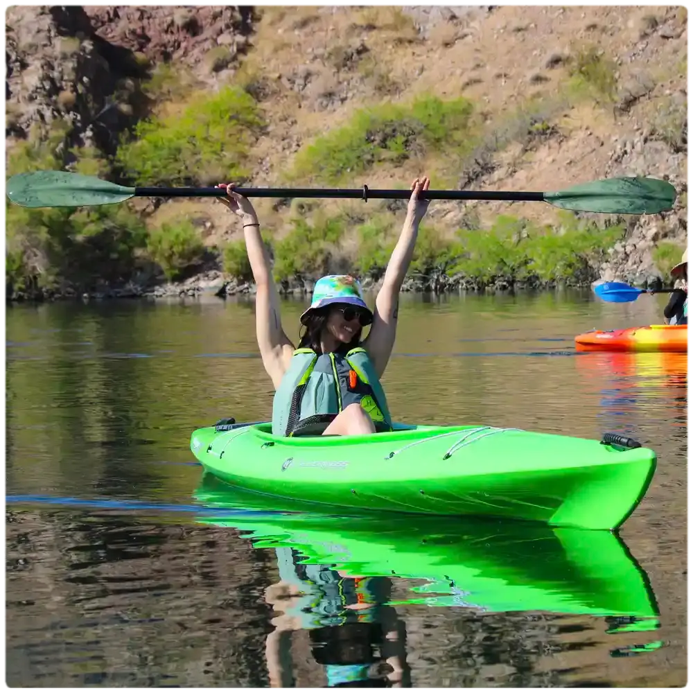 Guest raising a paddle in celebration on the river